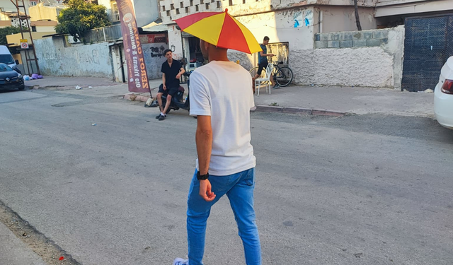 Aşırı sıcaklar sonrası çareyi başına şemsiye takmakta buldu!